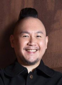 A headshot of a man smiling to camera