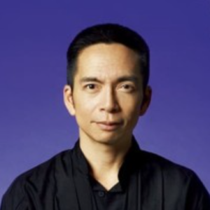 A headshot of a man with black hair against a blue background